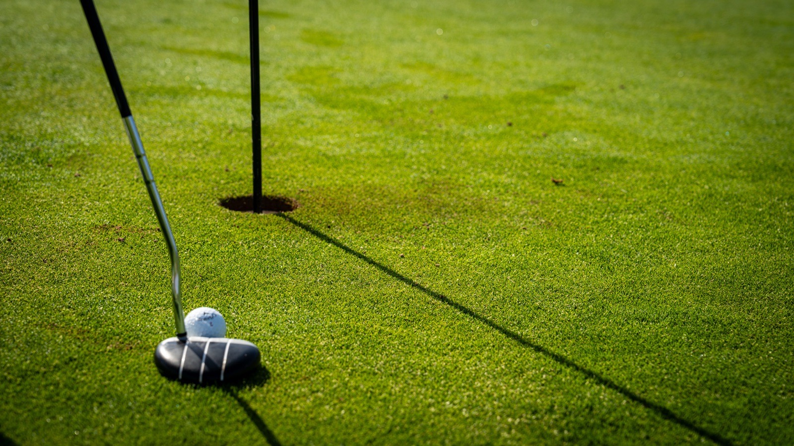Golfball am Lochrand im warmen Abendlicht
